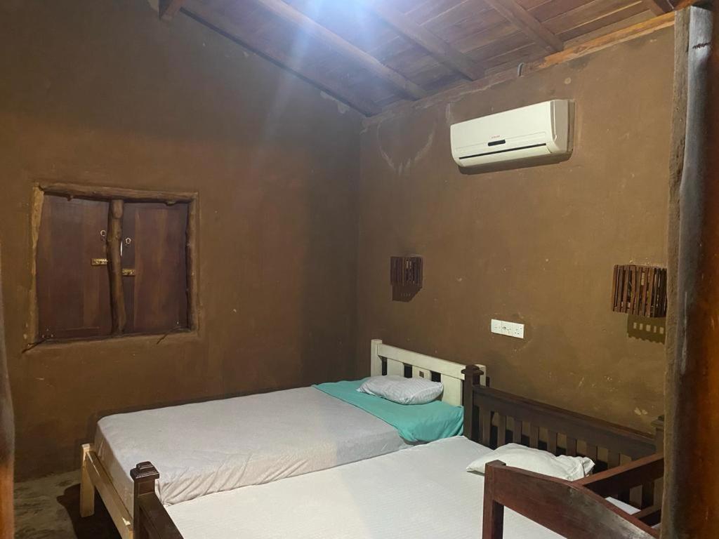 a bedroom with two beds and a air conditioner at Pokuna River Chalet in Ratkarawwa