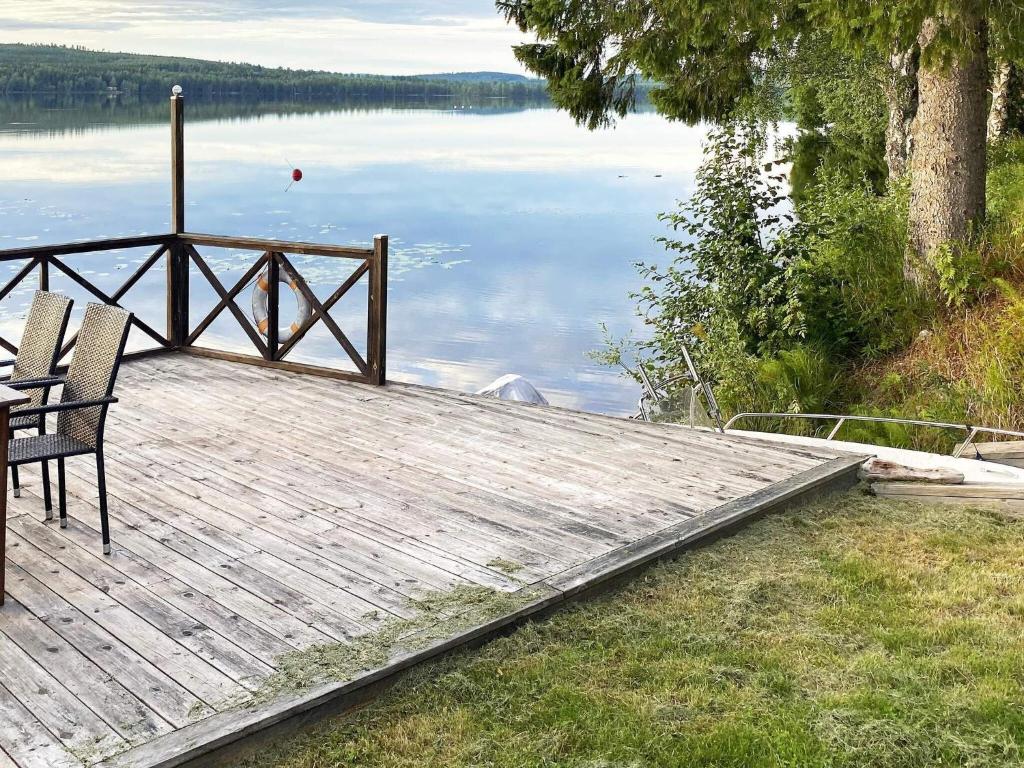 a wooden dock with a table and chairs on a lake at Holiday home TRÖNÖDAL in Vallsta