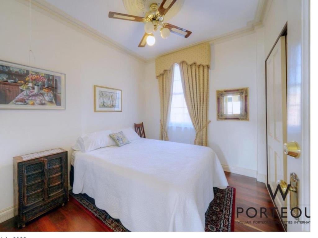- une chambre avec un lit blanc et un ventilateur de plafond dans l'établissement Quiet and peaceful Perth City living with free Parking, à Perth