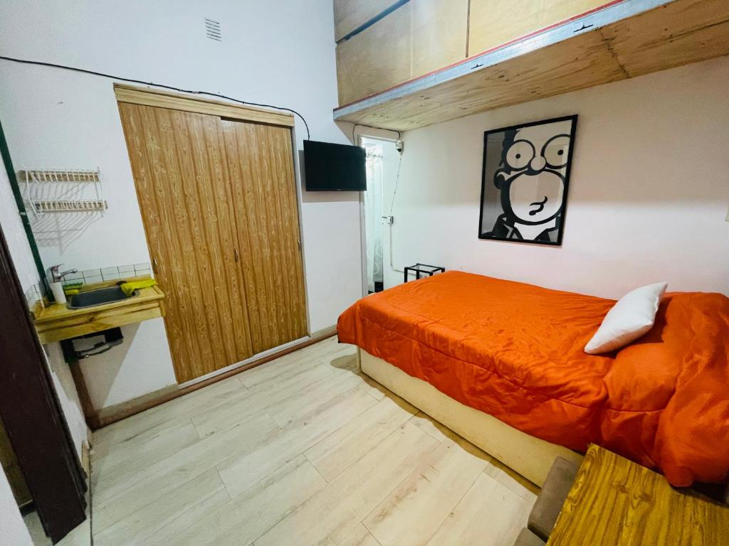1 dormitorio con cama de color naranja y suelo de madera en Rinconcito en Pompeya en Buenos Aires