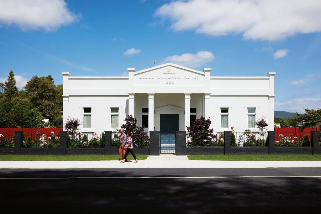 a woman walking in front of a white building at Kowhai Studio in Paeroa