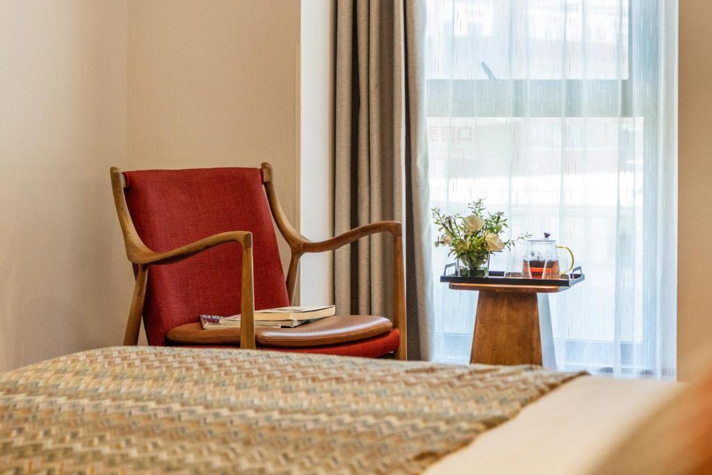 a bedroom with a bed and a chair and a window at Wuyu Hotel - Chongqing Jiangbei Airport & Light Rail in Chongqing