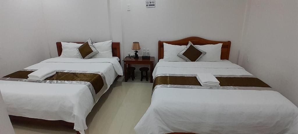 two twin beds in a room with a table at Khách sạn 68 ĐỒNG HẢI in Dong Hoi