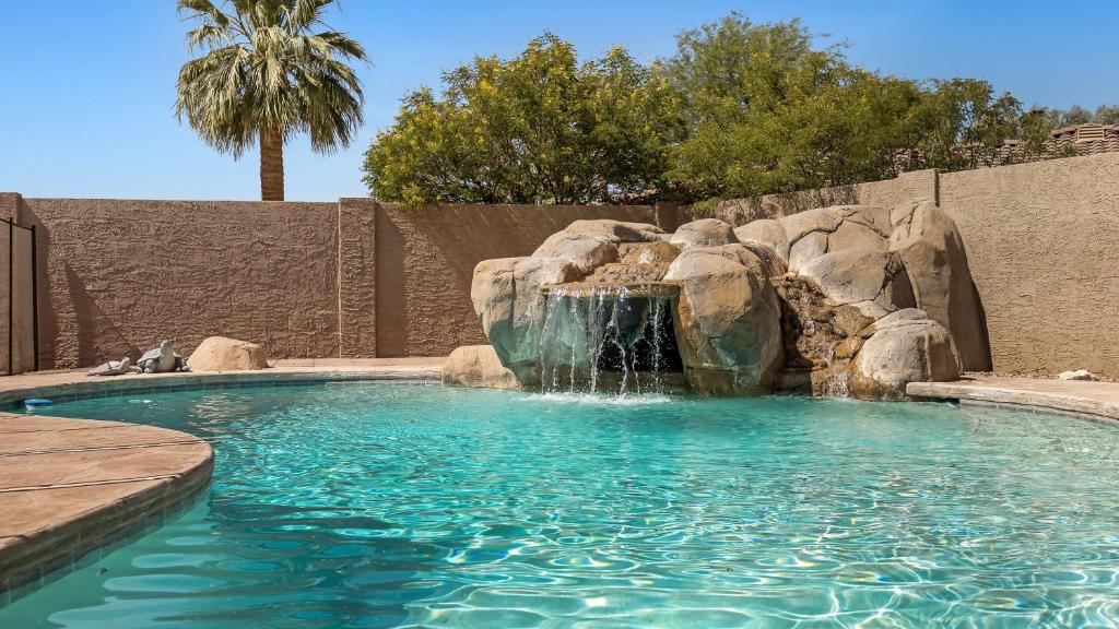 a swimming pool with a waterfall in a backyard at Luxe Central Scottsdale 4 bdrm w Backyard Oasis in Scottsdale