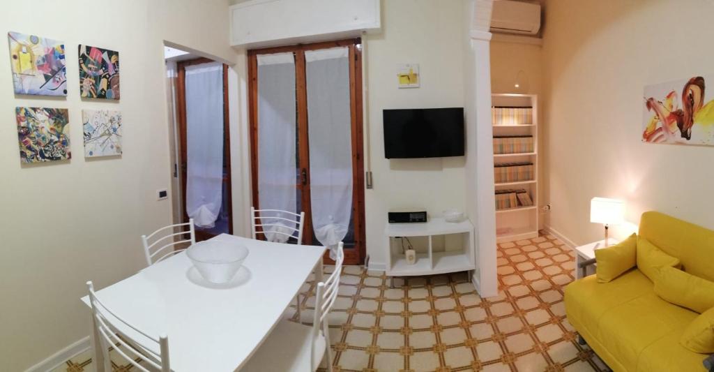 ein Wohnzimmer mit einem Tisch und einem gelben Sofa in der Unterkunft Casa MATERA - Bilocale Terminal Bus in Termoli