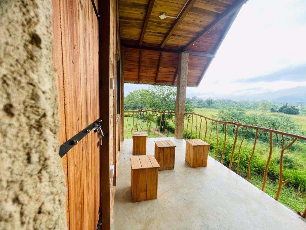 錫吉里亞的住宿－Prana Ayurveda Chalet- Sigiriya，阳台设有长椅,享有田野美景。