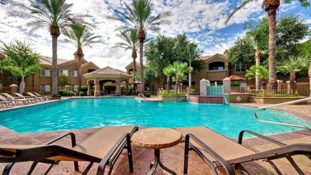 een zwembad met stoelen en palmbomen bij Cozy 1-Bdrm Scottsdale Condo next to pool in Scottsdale