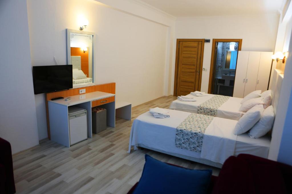 a bedroom with two beds and a desk and a television at Uğur Otel in Kas