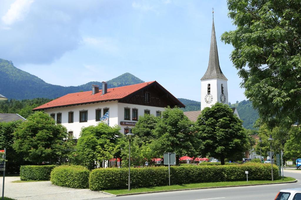 eine Kirche mit Kirchturm und ein Gebäude mit Uhrturm in der Unterkunft Gasthof Prinzregent Superior in Marquartstein