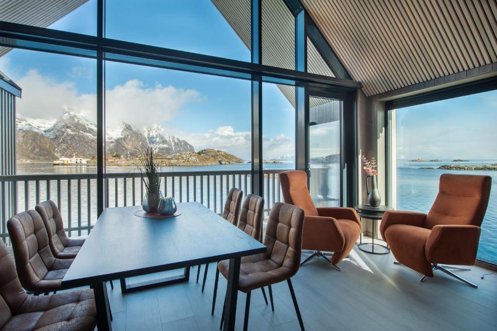 una sala da pranzo con tavolo, sedie e montagne di CornerView Apartment Henningsvær a Henningsvær