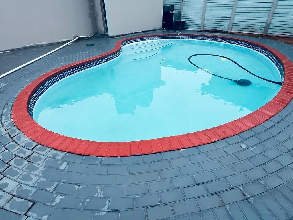 a large swimming pool with a red curb around it at Mudix Royal Palace Guest Lodge in Musina