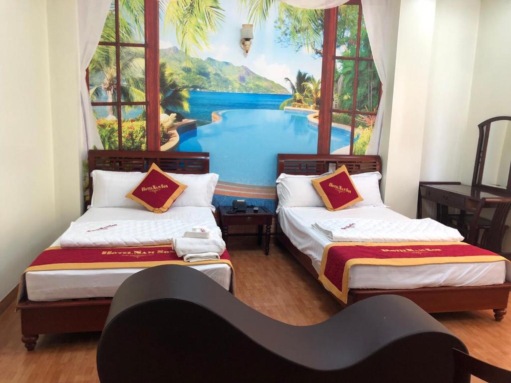 two beds in a room with a painting on the wall at Hotel Nam Sơn in Dực Liễn