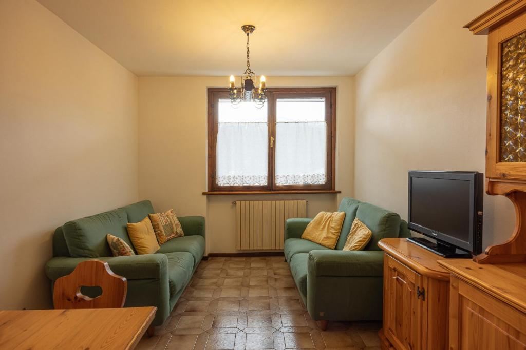 a living room with two green couches and a television at Casa alla Sorgente, con vista panoramica in San Vito di Cadore