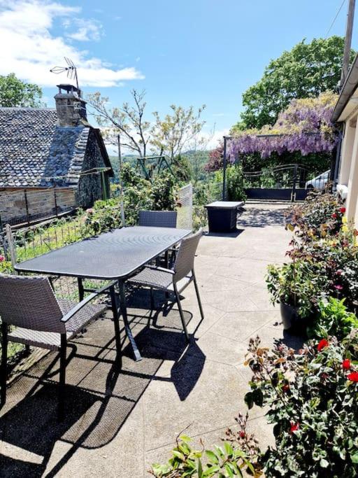 una mesa y sillas en un patio con flores en La Colline d'Estaing, Maison 4 pers avec terrasse en Estaing