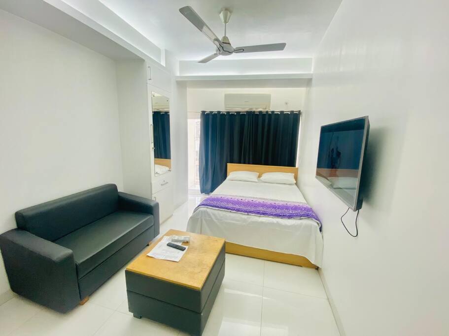 a bedroom with a bed and a chair and a couch at Cozy Studio Apartment Basundhara in Dhaka