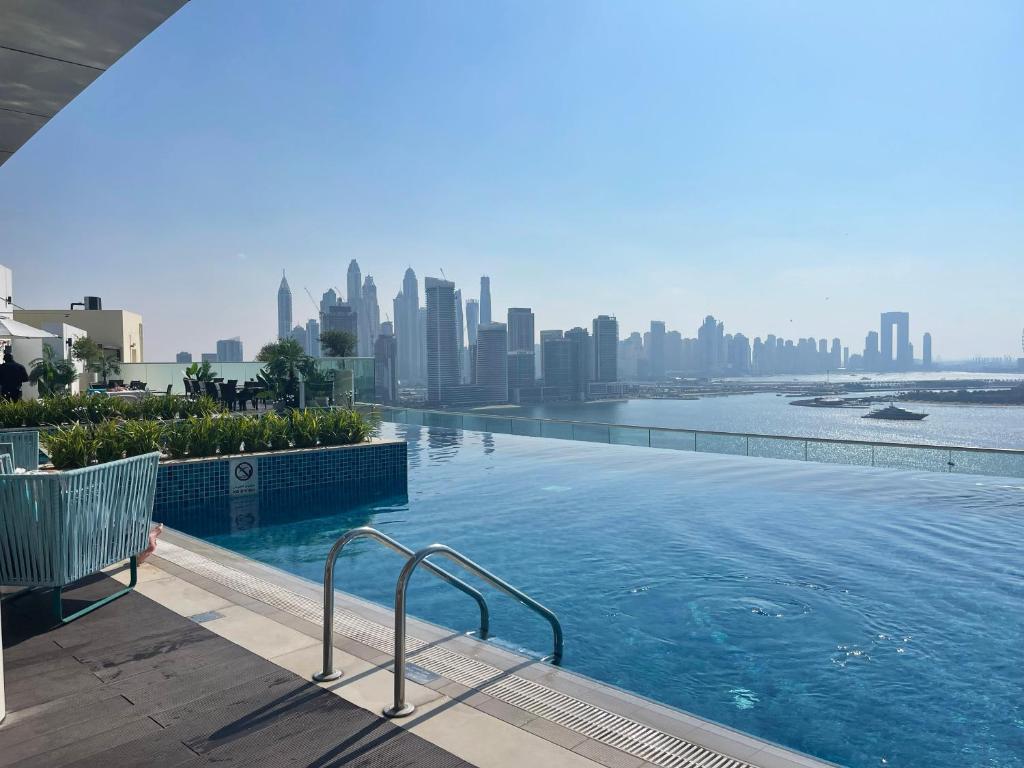 a swimming pool with a city skyline in the background at Seven Palm, Private beach, Infinity Pool, High Floor 3BDR in Dubai