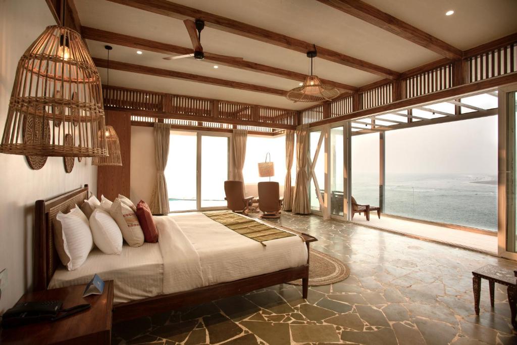 een slaapkamer met een bed en uitzicht op de oceaan bij SaffronStays Athaang, Dapoli in Ānjarle