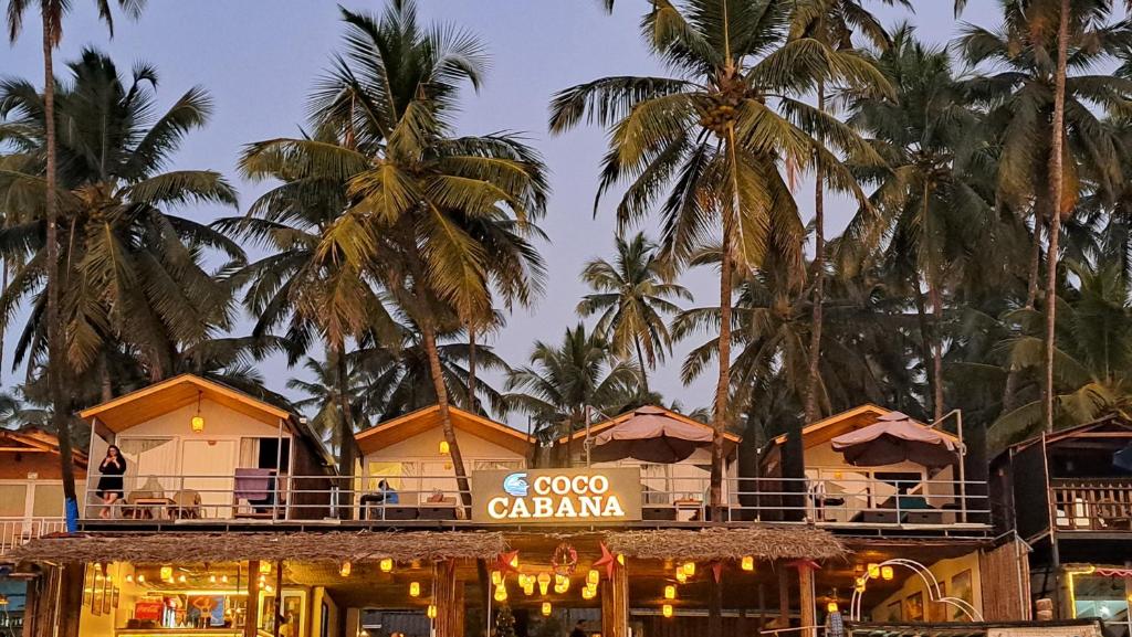 a restaurant with palm trees in the background at COCO CABANA in Palolem