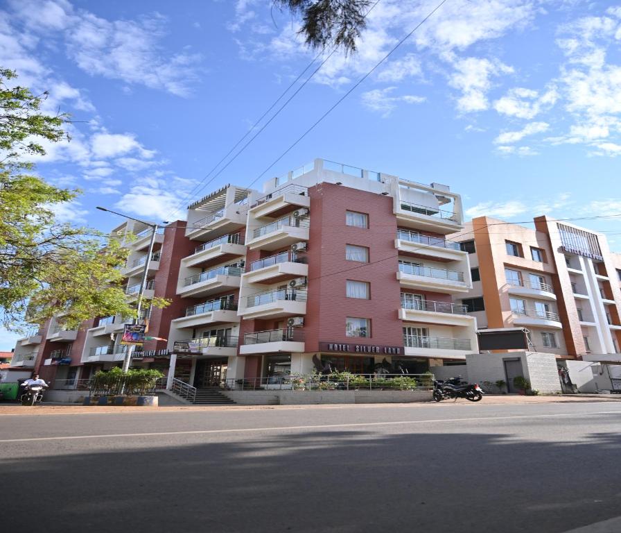 um grande edifício de apartamentos cor-de-rosa ao lado de uma rua em Hotel Silver Land New Digha em Digha