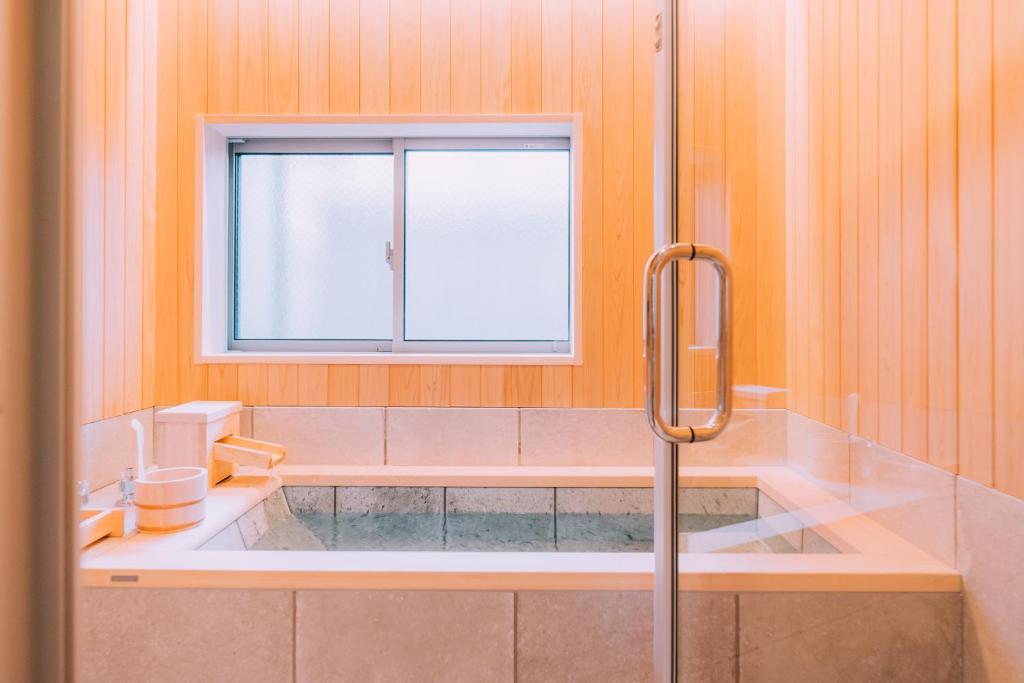 a bathroom with a tub and a window at One Harajuku: Private Oasis in Tokyo