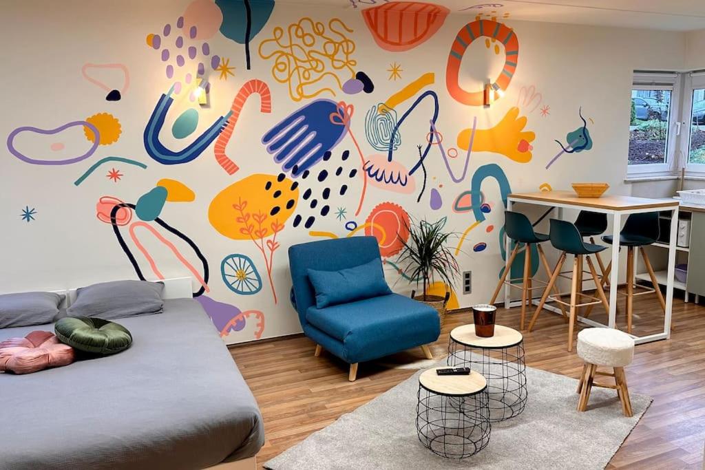 a bedroom with a wall with a colorful mural at Le studio Héloïse - BeCosy rentals - 2 ad + 1 enf in Péruwelz