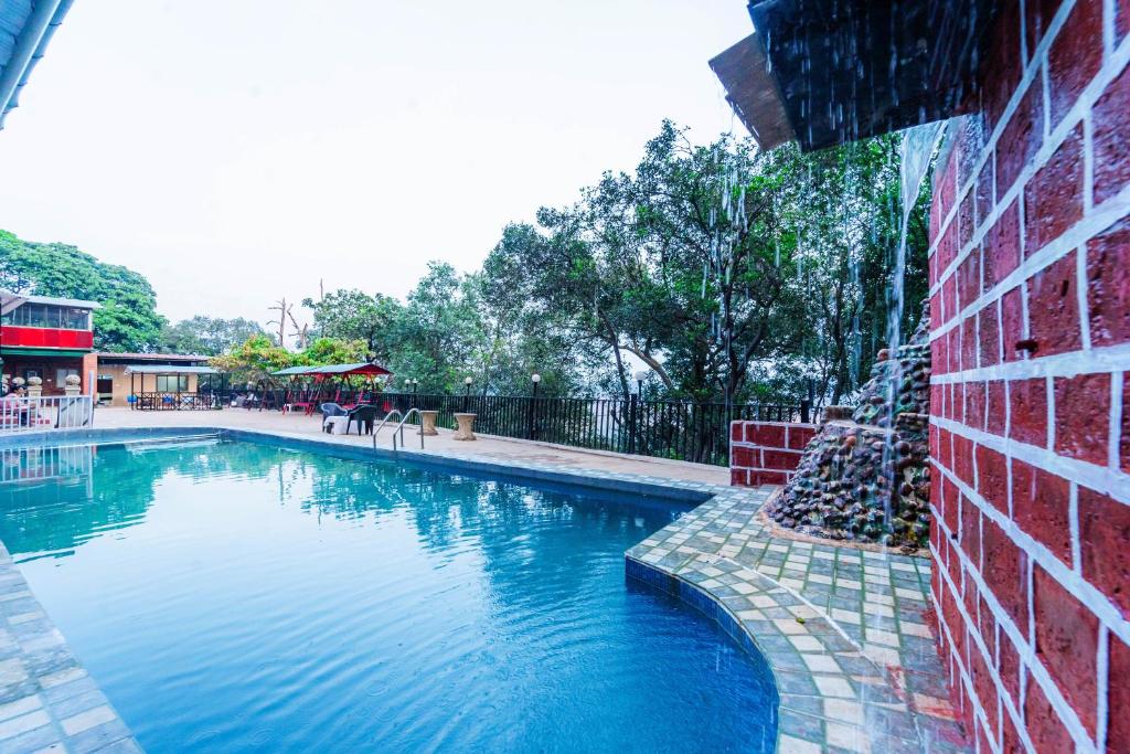 una gran piscina junto a un edificio de ladrillo en Itsy By Treebo- Sun N Shade en Matheran