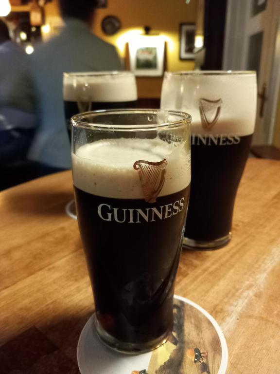 two glasses of beer sitting on a wooden table at Sunny Rooms near town centre in Warrenpoint