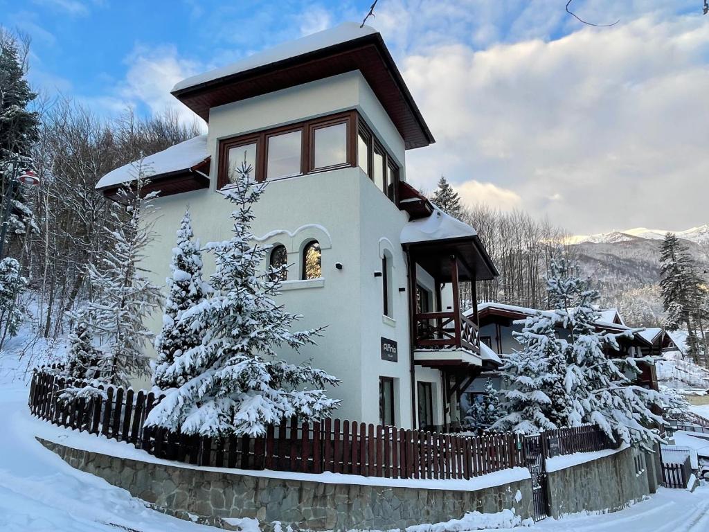 una casa cubierta de nieve con una valla y árboles en Alfinio Villa, en Sinaia