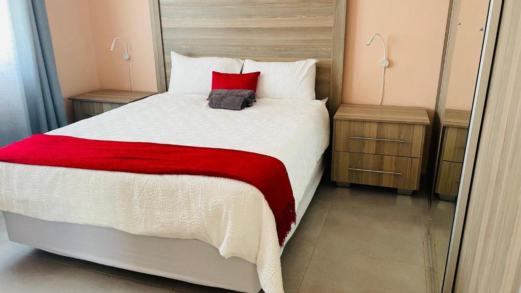 een slaapkamer met een groot bed en een rode deken bij Sol Place self catering units in Aliwal North