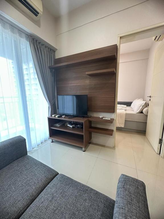 ein Wohnzimmer mit einem Sofa und einem Flachbild-TV in der Unterkunft Tanglin Orchard Apartment by Kondoku in Lontar