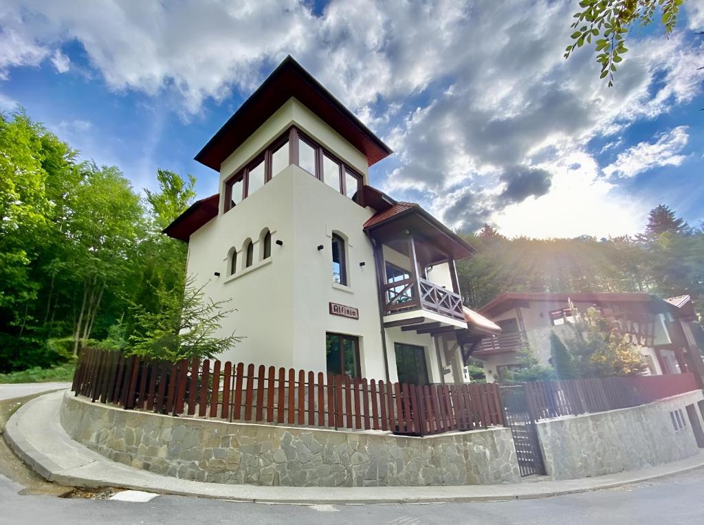 una grande casa bianca con una recinzione in legno di Alfinio Villa a Sinaia