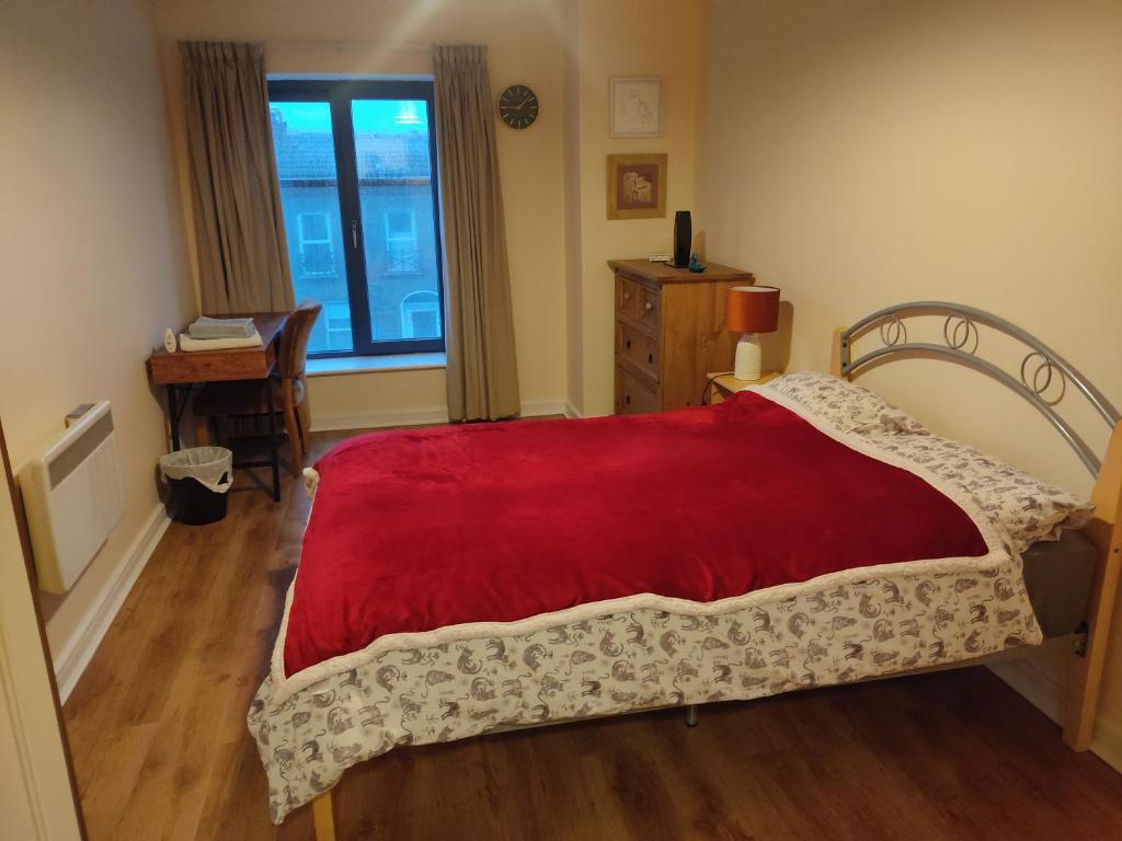 una camera da letto con un letto con una coperta rossa e una finestra di Spacious bright double bedroom with ensuite bathroom a Dublino
