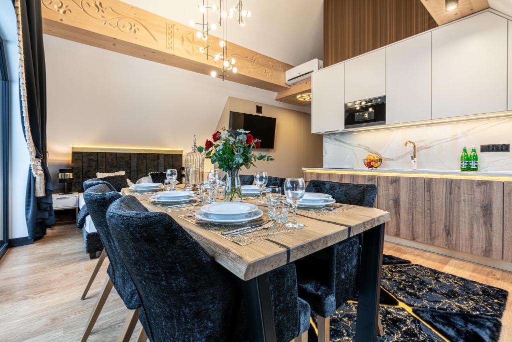 Dining table set for meal with floral centerpiece, plush chairs and modern kitchenette in background