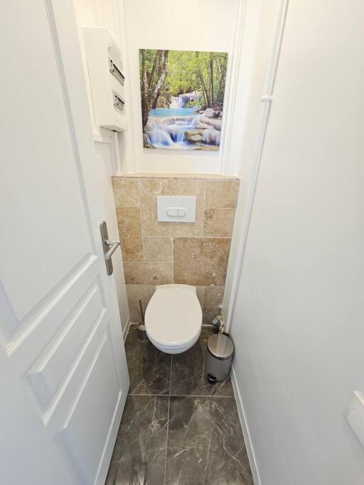 a white toilet in a bathroom with a door at Charmant appartement proche Paris in Épinay-sur-Seine