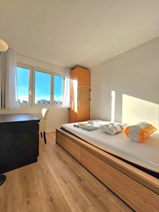 a bedroom with a large bed and a desk at Charmant appartement proche Paris in Épinay-sur-Seine