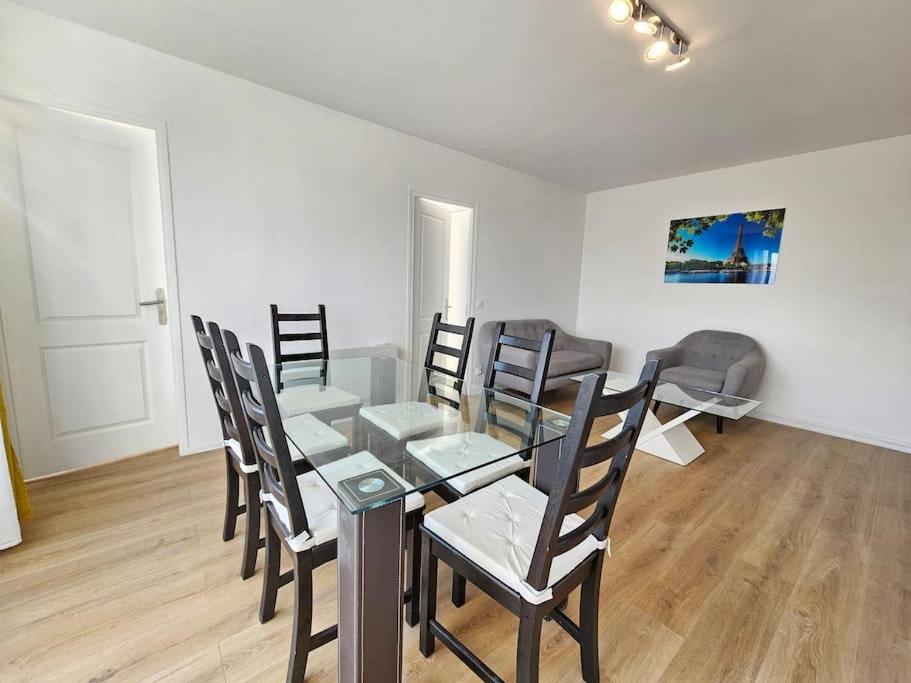 a dining room with a glass table and chairs at Charmant appartement proche Paris in Épinay-sur-Seine
