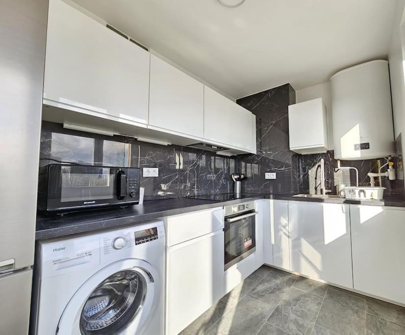 a kitchen with a washing machine and a microwave at Charmant appartement proche Paris in Épinay-sur-Seine