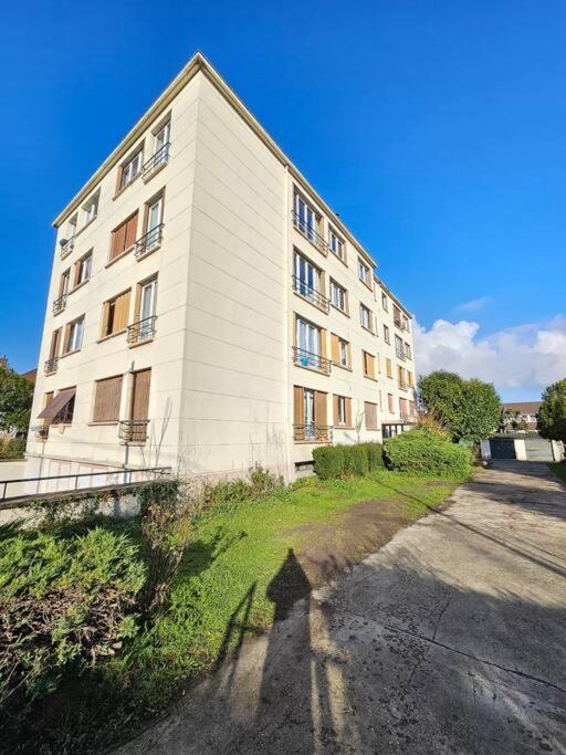 a large white building on the side of a road at Charmant appartement proche Paris in Épinay-sur-Seine