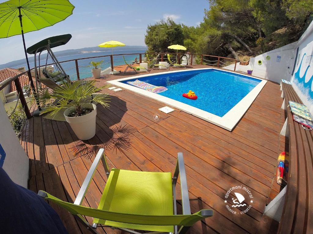 una terraza de madera con piscina en una casa en Apartments Mistral en Mimice