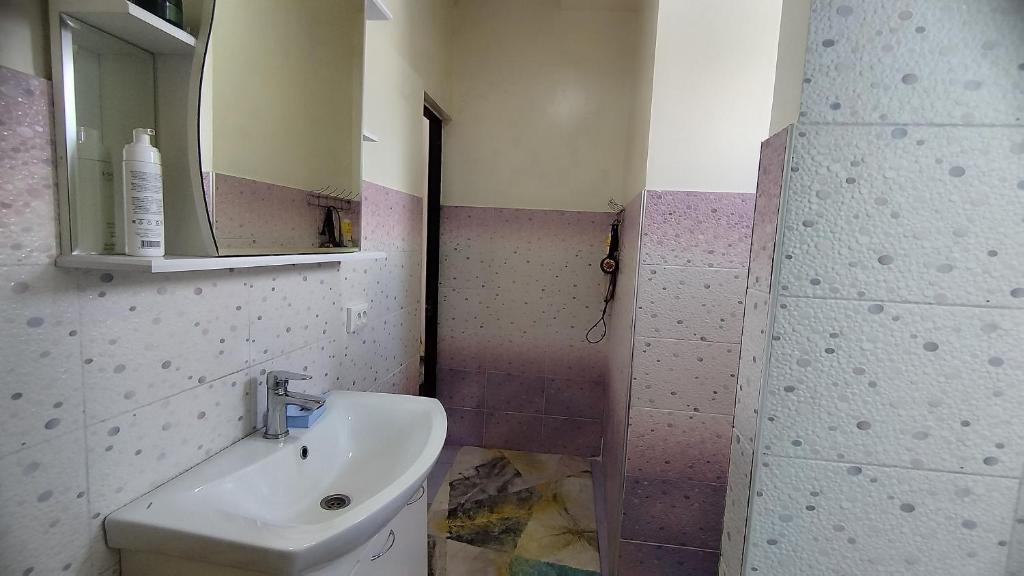 ein Bad mit einem Waschbecken und einem Spiegel in der Unterkunft Гостевой дом Datka in Karakol