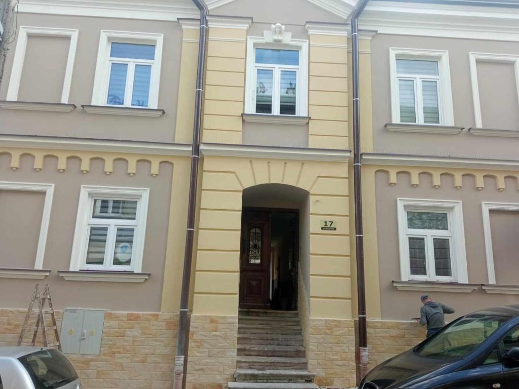 a yellow house with a door and stairs in front at Rafaelo Władycze 17/4 in Przemyśl