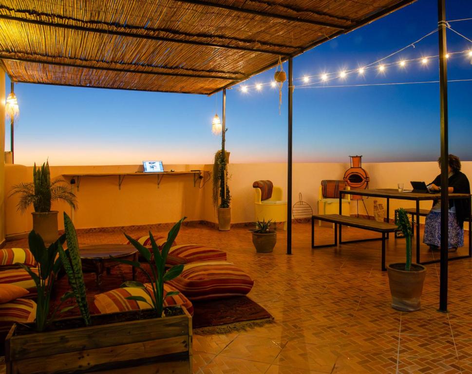 a room with a person sitting at a table with a laptop at Monkey's Guest House - Appartement roof top terrasse privée vue sur mer in Tamraght Ouzdar