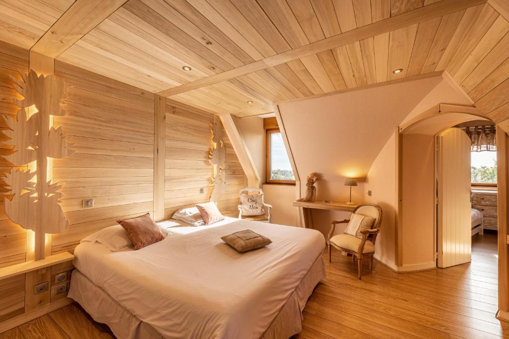 Un dormitorio con una cama grande en una habitación con techos de madera. en Les Maisons de Montagne - Chez Marie, en Pailherols
