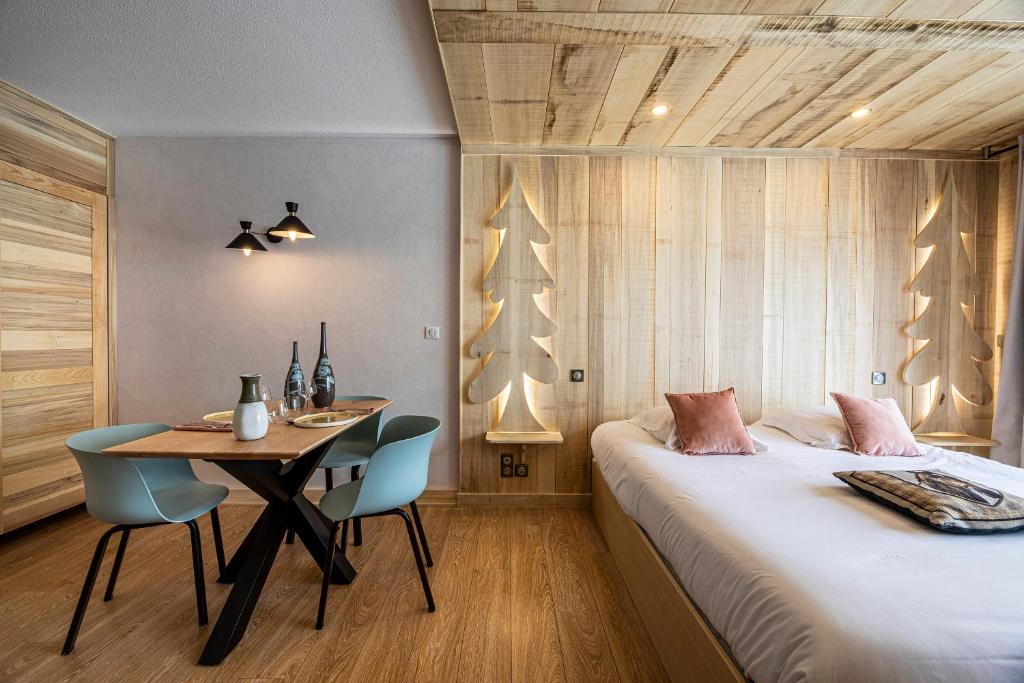a bedroom with a bed and a table with chairs at Les Maisons de Montagne - Chez Marie in Pailherols