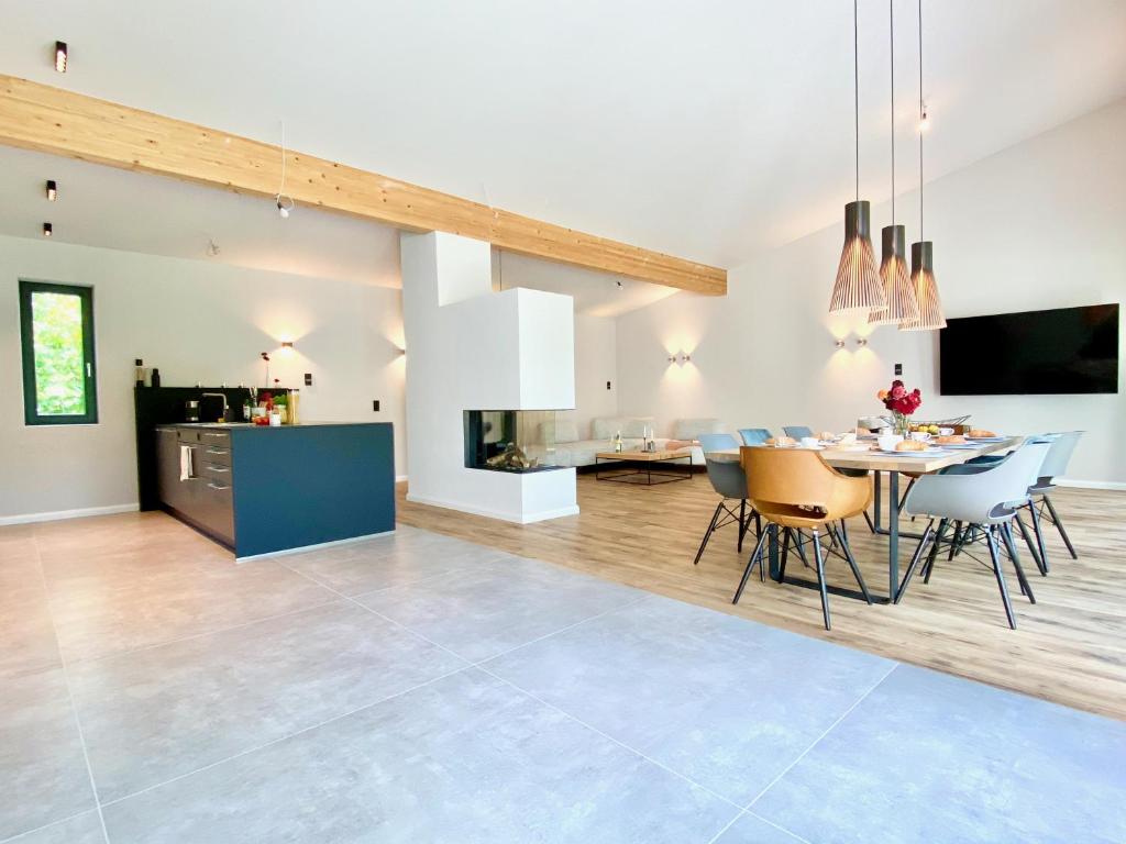 Snug Stays Design Villa mit Garten zentral aber ruhig 400m zum Ammersee في ديسن آم أميرسي: غرفة طعام وغرفة معيشة مع طاولة وكراسي