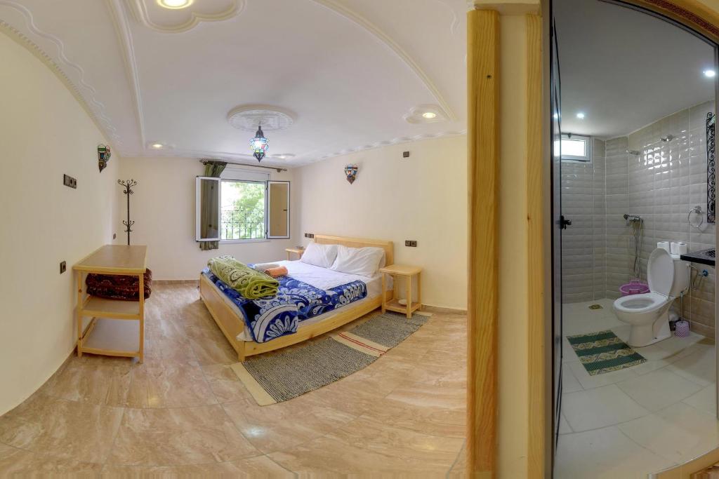 um quarto com uma cama e uma casa de banho com um chuveiro em Hotel De La Vallée em Aït Baha