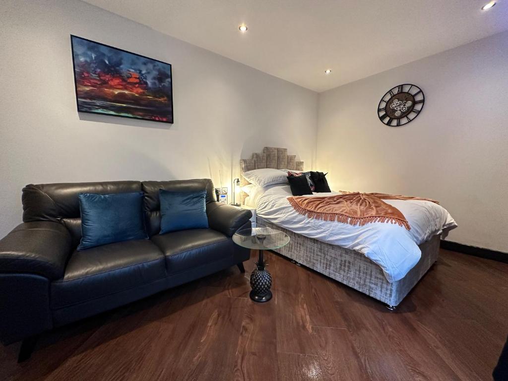 a bedroom with a couch and a bed and a clock at The Cottage Hideout in Upholland