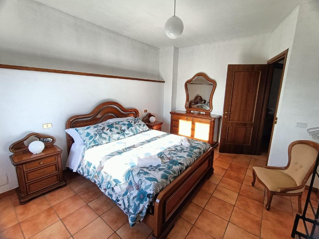 una camera con letto, sedia e specchio di A Casa dei Nonni a San Demetrio neʼ Vestini