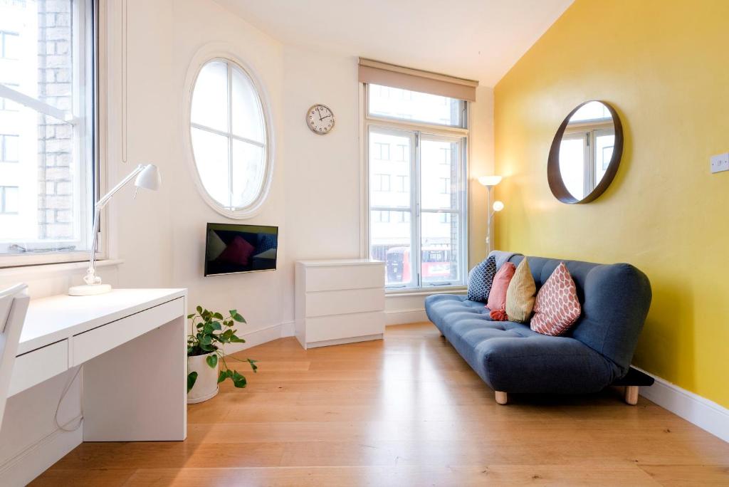 a living room with a blue couch and two windows at Apartments are located in the Heart of Shoreditch in London