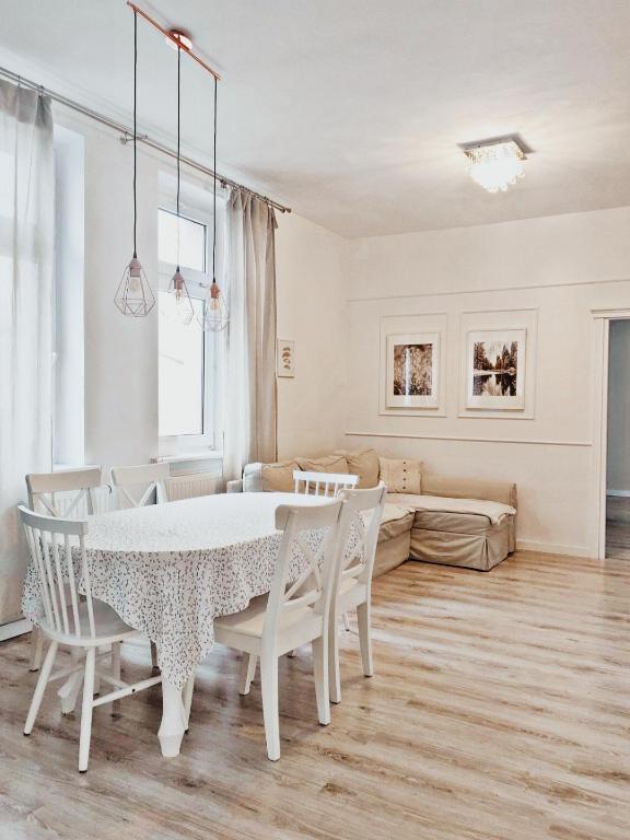 a white dining room with a table and chairs at Żnin City in Żnin